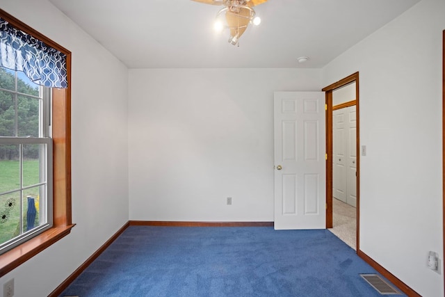empty room with baseboards, dark colored carpet, and visible vents
