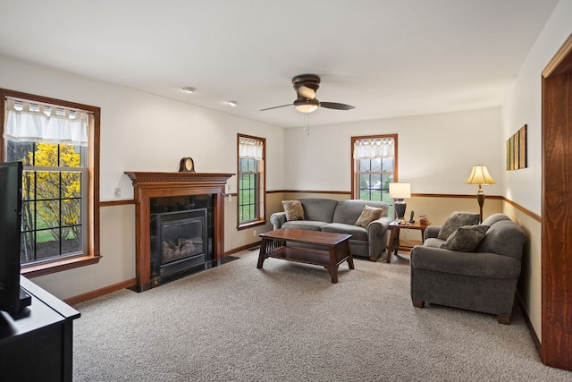carpeted living area with baseboards, a ceiling fan, and a fireplace with flush hearth