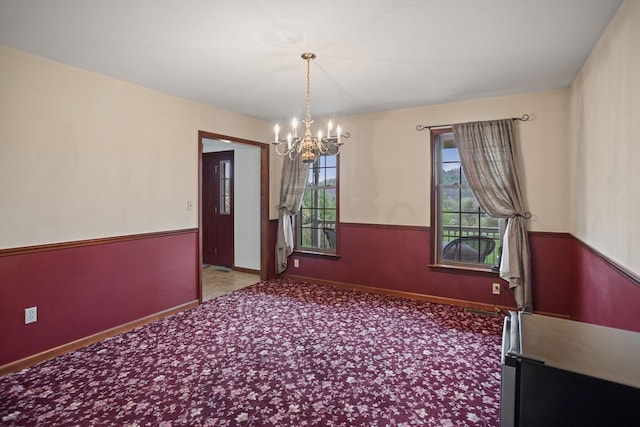 unfurnished dining area with a chandelier, baseboards, and carpet floors