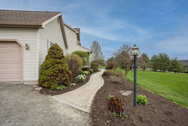 view of home's exterior featuring a yard, a shingled roof, and a garage