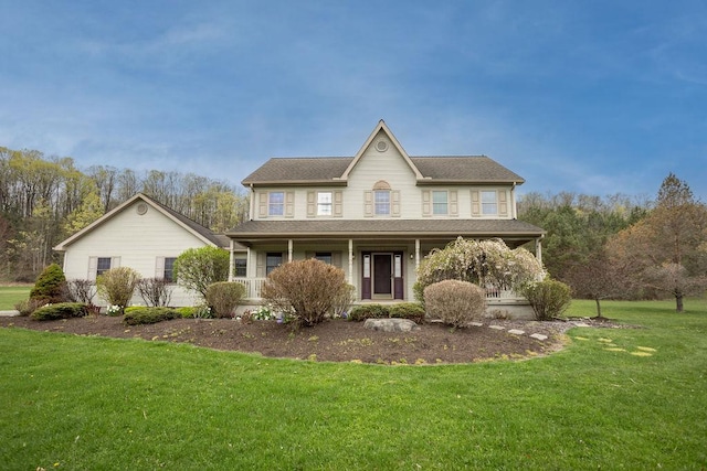 view of front of house featuring a front yard, a shingled roof, and covered porch