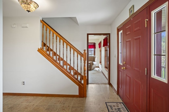 entrance foyer featuring stairs, baseboards, and plenty of natural light