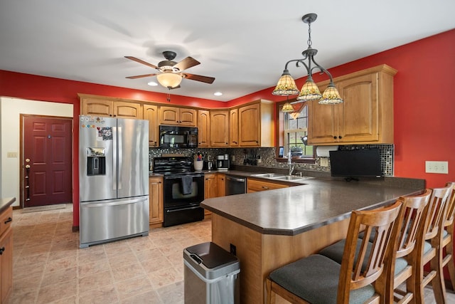 kitchen featuring black appliances, dark countertops, backsplash, a sink, and a peninsula