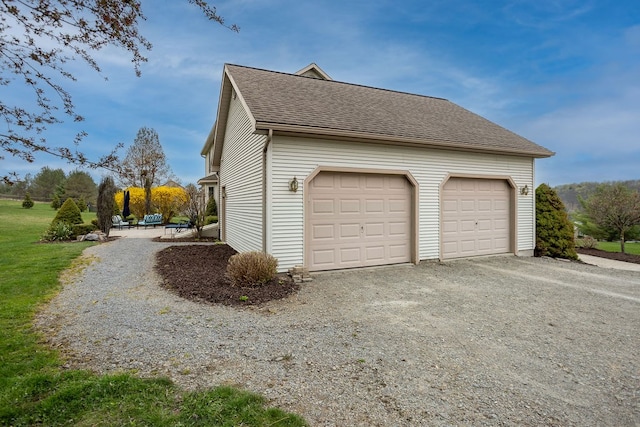 view of side of home with driveway and a shingled roof