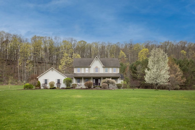 traditional-style home featuring a porch, a front yard, and a view of trees