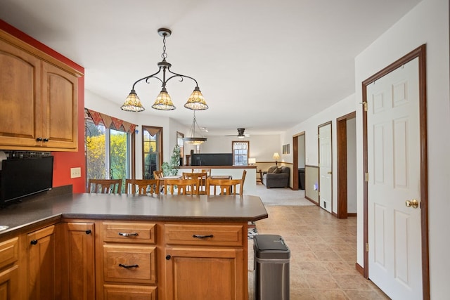 kitchen featuring decorative light fixtures, a peninsula, open floor plan, and plenty of natural light