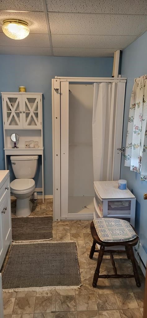 bathroom featuring vanity, a paneled ceiling, toilet, and walk in shower