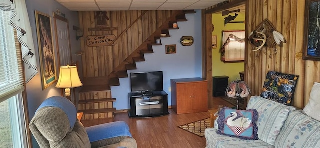 living room featuring a paneled ceiling, hardwood / wood-style flooring, and wood walls