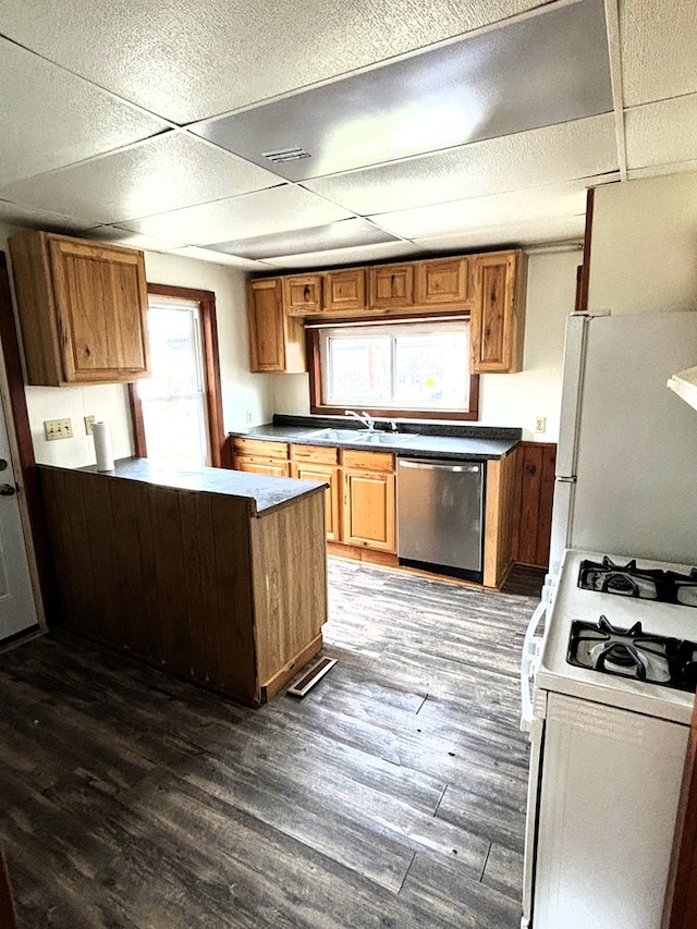 kitchen featuring white appliances, a drop ceiling, dark wood-type flooring, and sink