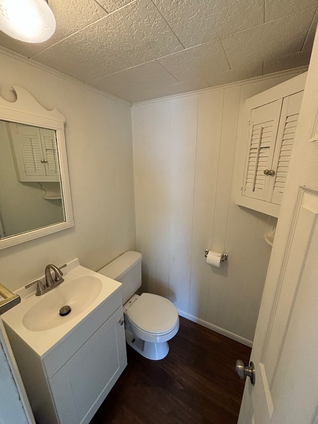 bathroom featuring vanity, hardwood / wood-style flooring, toilet, and wooden walls