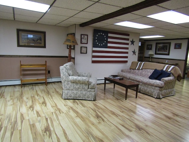 living room with a baseboard heating unit, a paneled ceiling, and light wood-type flooring