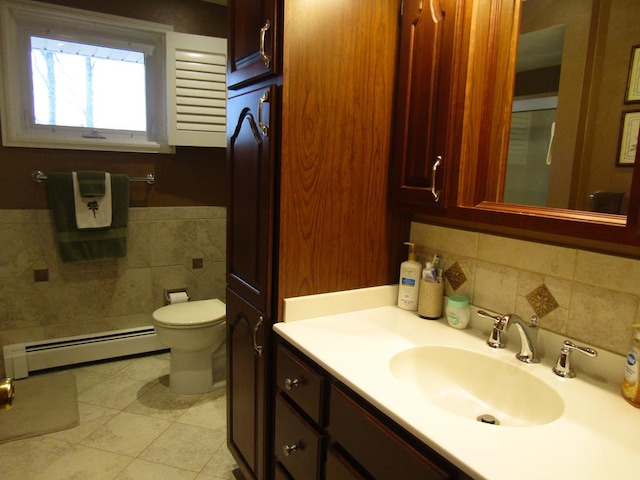 bathroom with toilet, tile walls, baseboard heating, vanity, and tile patterned flooring