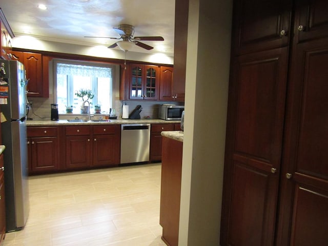 kitchen with sink, ceiling fan, stainless steel appliances, light stone countertops, and decorative backsplash