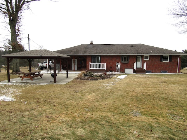 rear view of house with a gazebo, a patio area, and a lawn