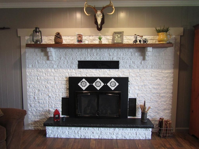 interior details featuring crown molding, a stone fireplace, and hardwood / wood-style flooring