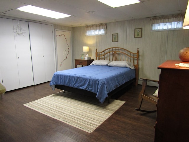 bedroom with dark wood-type flooring, a paneled ceiling, and baseboard heating