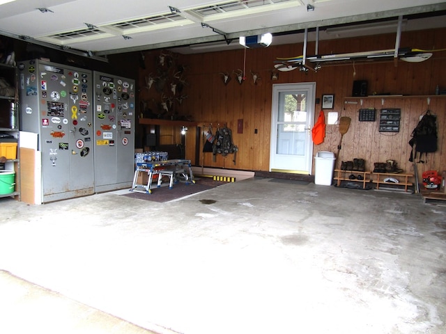 garage featuring a garage door opener, wood walls, and a workshop area