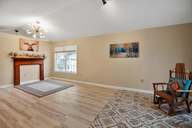 sitting room with hardwood / wood-style flooring, a chandelier, and vaulted ceiling