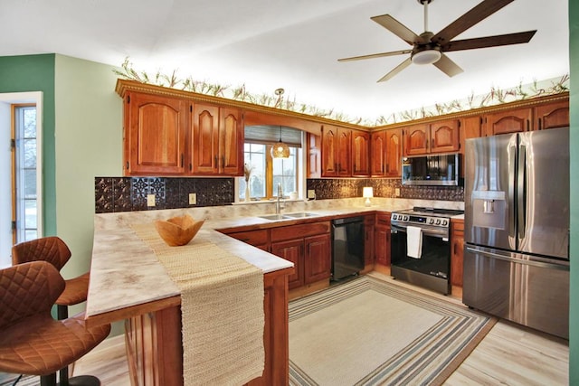 kitchen featuring kitchen peninsula, ceiling fan, sink, light wood-type flooring, and stainless steel appliances