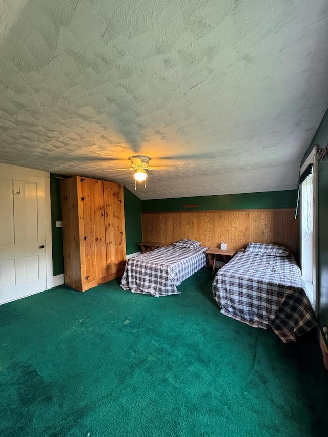 unfurnished bedroom featuring carpet flooring, ceiling fan, a textured ceiling, and wooden walls