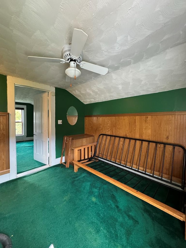 unfurnished bedroom featuring vaulted ceiling, ceiling fan, carpet, and a textured ceiling