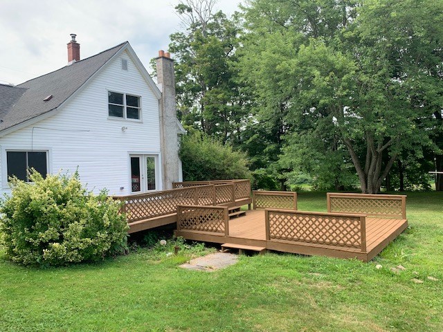 rear view of property featuring french doors, a yard, and a wooden deck