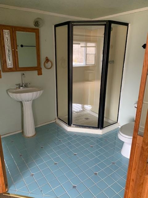 bathroom with toilet, tile patterned floors, and walk in shower