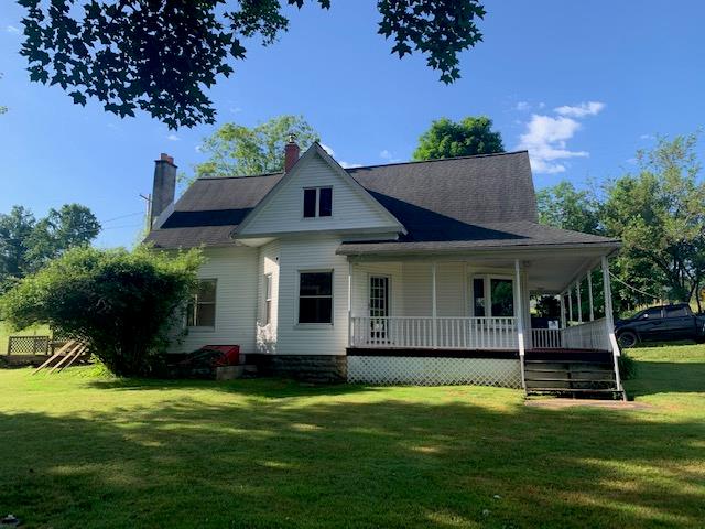 rear view of property featuring covered porch and a yard