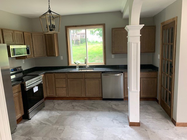 kitchen featuring ornate columns, sink, a notable chandelier, pendant lighting, and appliances with stainless steel finishes