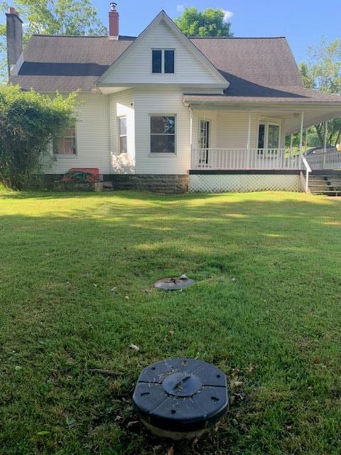 rear view of property with a lawn and a porch