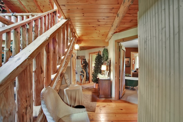 stairs featuring beam ceiling, wood ceiling, and hardwood / wood-style flooring