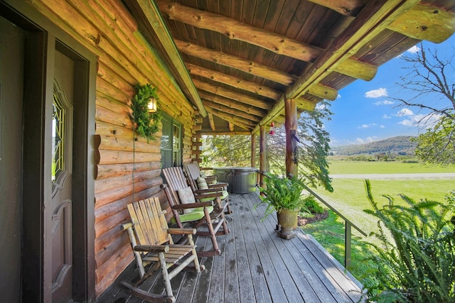 wooden deck with a mountain view, a porch, and a lawn