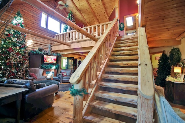 staircase with rustic walls, beamed ceiling, high vaulted ceiling, wood ceiling, and hardwood / wood-style flooring