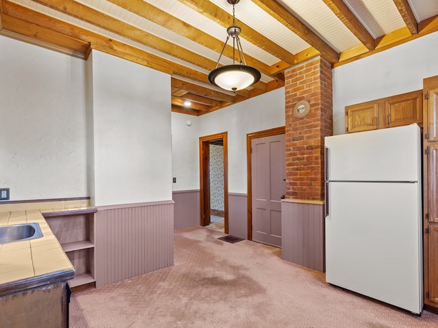 kitchen with light colored carpet, pendant lighting, white refrigerator, tile countertops, and beam ceiling