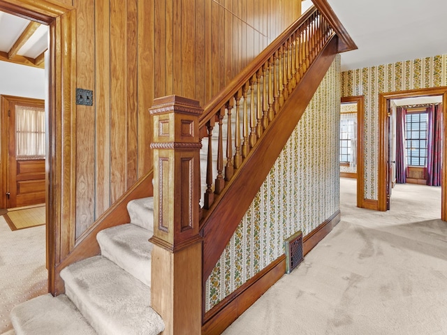 stairway with carpet flooring and wood walls