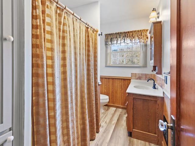 bathroom with vanity, hardwood / wood-style flooring, toilet, and wood walls