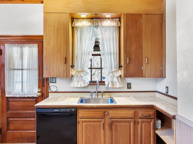 kitchen with black dishwasher, tile counters, and sink