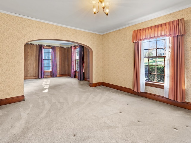 unfurnished room with carpet flooring, crown molding, and an inviting chandelier