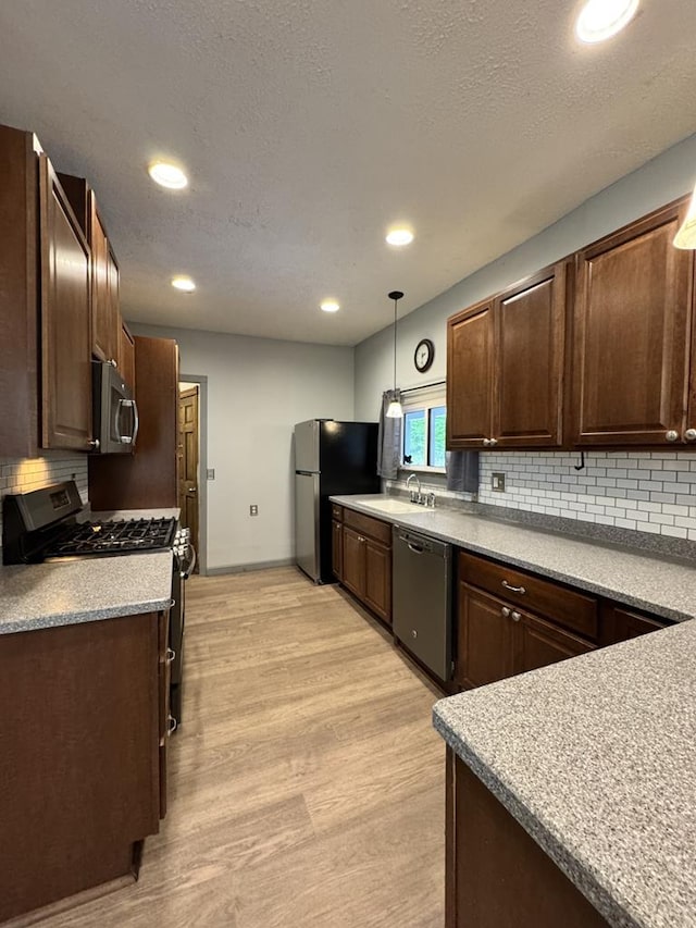 712 W Main St, Smethport, PA 16749 - kitchen with stainless steel appliances, a sink, decorative backsplash, hanging light fixtures, and light wood-style flooring