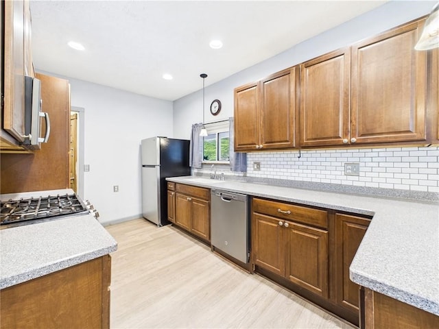 712 W Main St, Smethport, PA 16749 - kitchen featuring appliances with stainless steel finishes, light wood-style floors, backsplash, light countertops, and decorative light fixtures