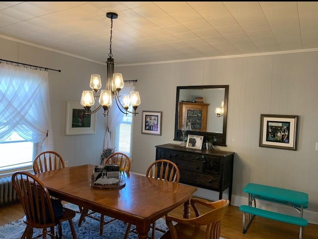 dining area with a chandelier, wood-type flooring, and ornamental molding