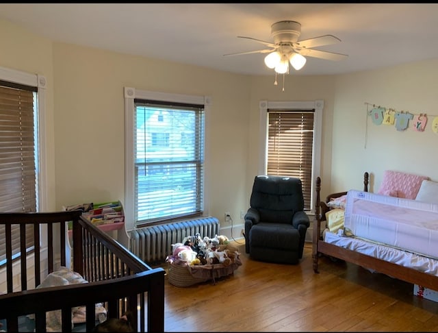 bedroom with hardwood / wood-style floors, ceiling fan, and radiator