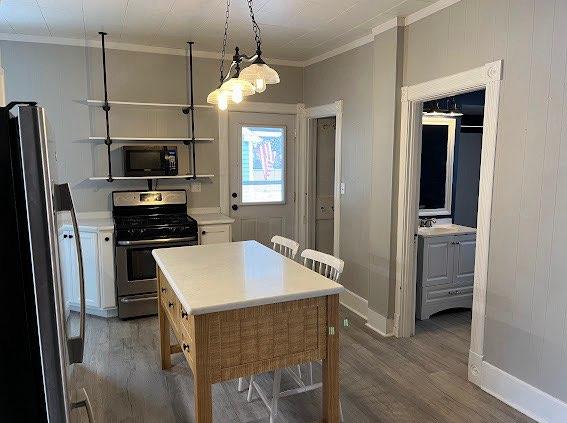 kitchen featuring hanging light fixtures, ornamental molding, appliances with stainless steel finishes, dark hardwood / wood-style flooring, and white cabinetry