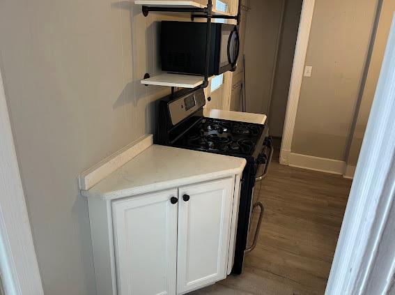 kitchen with white cabinets, dark wood-type flooring, and range