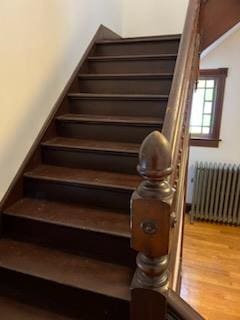 stairs with hardwood / wood-style flooring and radiator