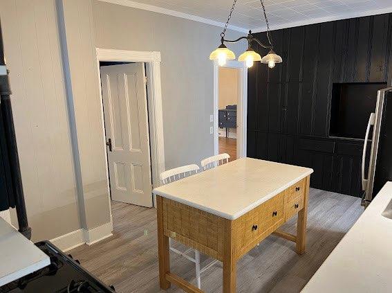 interior space featuring pendant lighting, refrigerator, hardwood / wood-style flooring, ornamental molding, and a notable chandelier