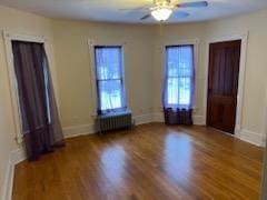 empty room featuring hardwood / wood-style floors, ceiling fan, and radiator heating unit