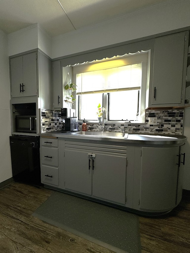 kitchen with tasteful backsplash, a healthy amount of sunlight, dark wood-type flooring, and sink