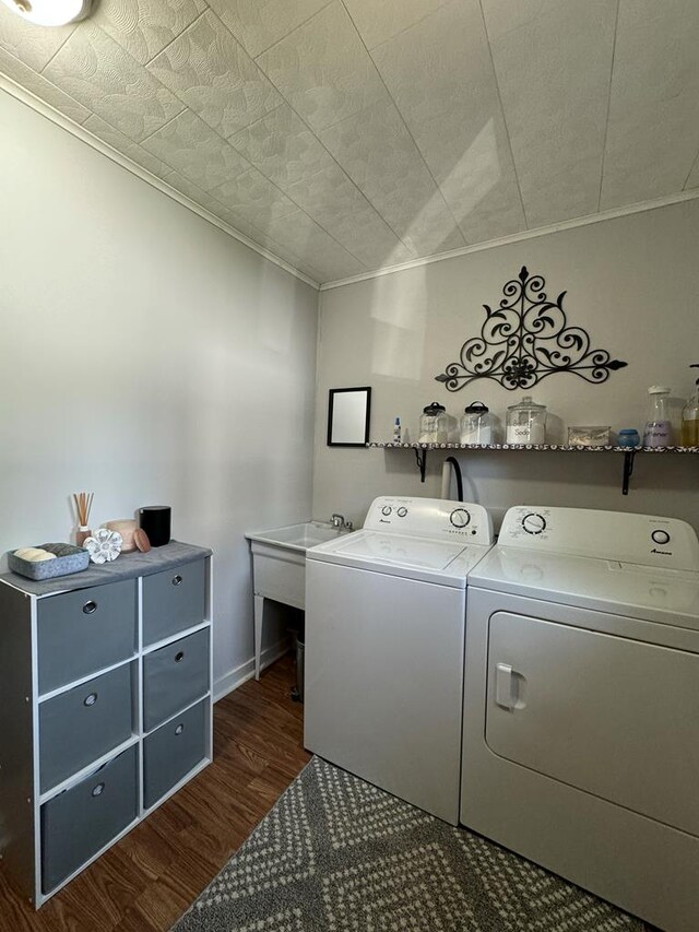 clothes washing area featuring dark hardwood / wood-style floors, ornamental molding, and washer and dryer