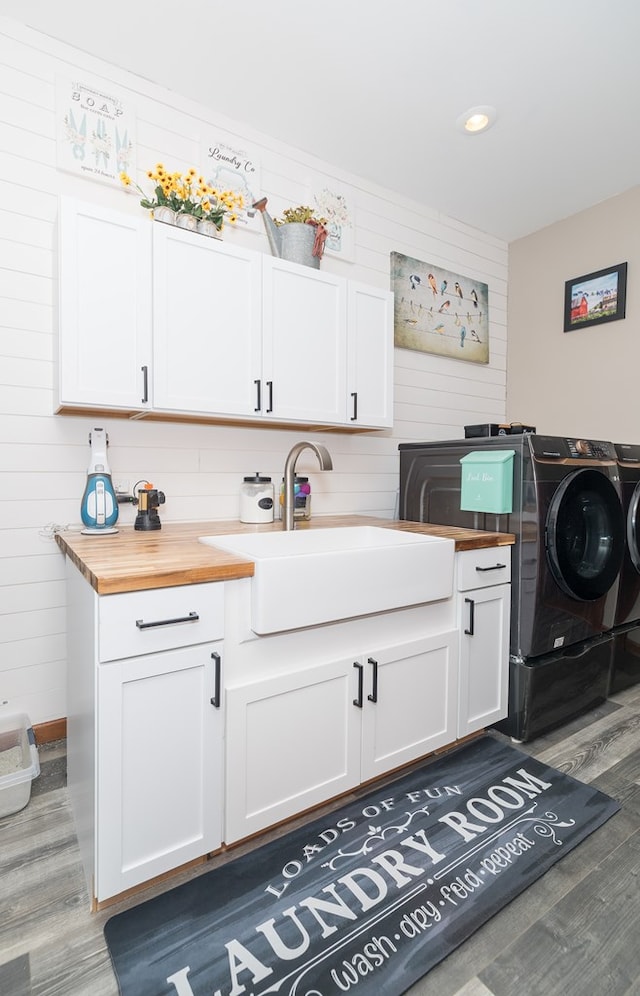 washroom with cabinet space, washer and dryer, wood finished floors, and a sink